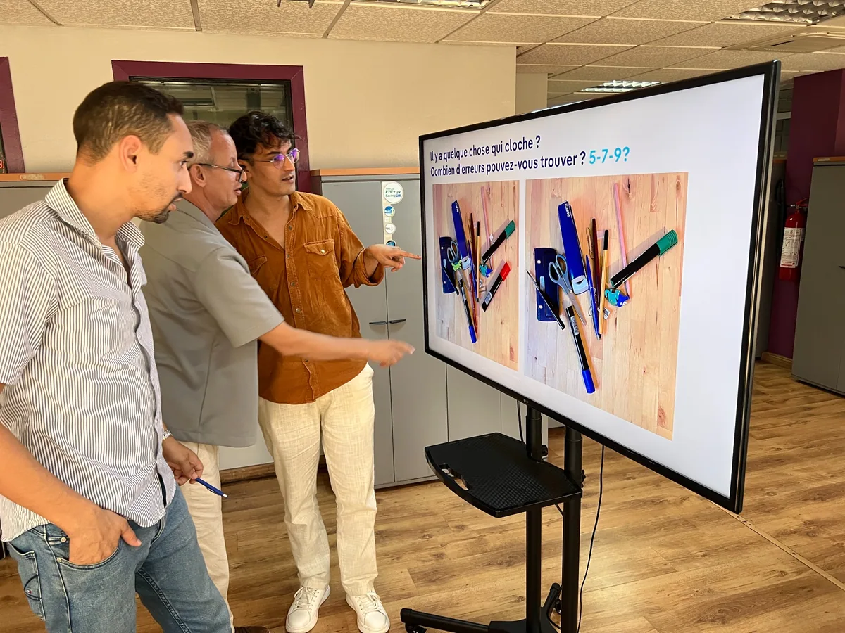 Trois participants comparent deux images pendant la formation chez Radio Plus.